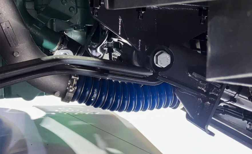Mangueira intercooler azul Flexfab instalada sob a cabine de um caminhão, mostrando o mangote de silicone reforçado e abraçadeira metálica conectando o sistema de ar de pressurização do intercooler.